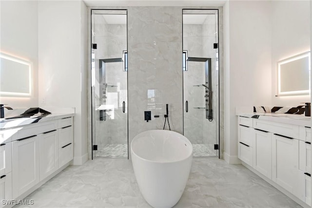 full bath with a stall shower, marble finish floor, two vanities, and a soaking tub