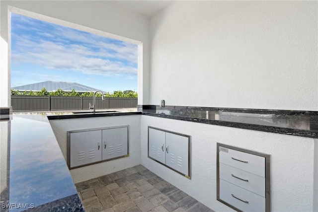 view of patio / terrace with fence, an outdoor kitchen, and a sink