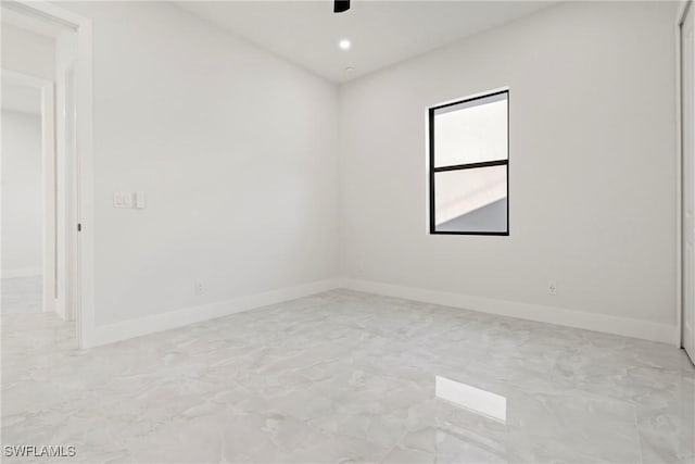 empty room with marble finish floor, baseboards, and a ceiling fan