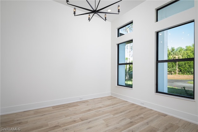 unfurnished room with light wood-type flooring, a chandelier, and a wealth of natural light