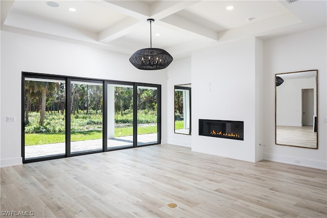 unfurnished living room featuring coffered ceiling, beam ceiling, a healthy amount of sunlight, and light wood-type flooring