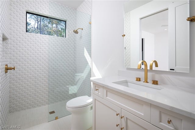 bathroom with toilet, vanity, and tiled shower