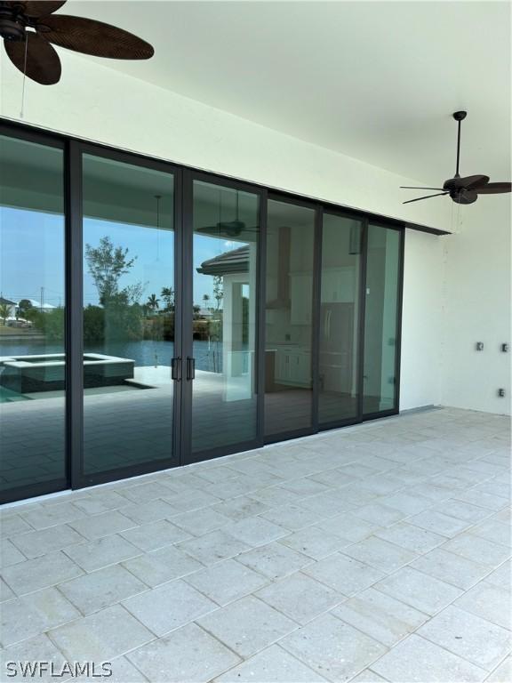 view of patio / terrace featuring ceiling fan, a water view, and french doors