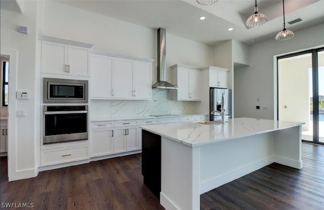 kitchen featuring pendant lighting, wall chimney exhaust hood, white cabinets, and appliances with stainless steel finishes