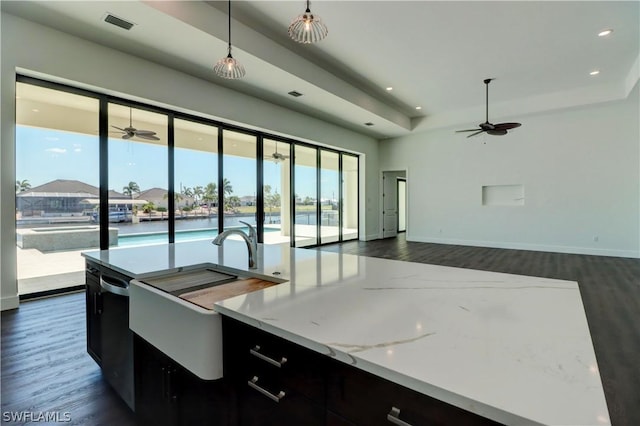 kitchen featuring dark hardwood / wood-style floors, a kitchen island with sink, hanging light fixtures, and ceiling fan