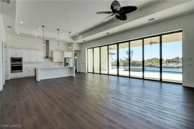 unfurnished living room with a towering ceiling, dark hardwood / wood-style flooring, and ceiling fan