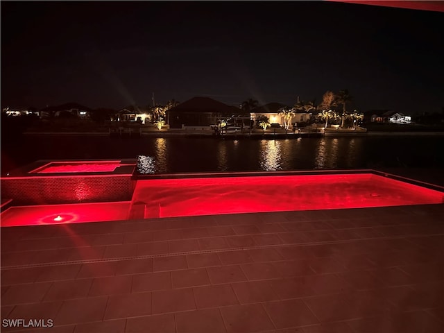 exterior space with an in ground hot tub and a water view