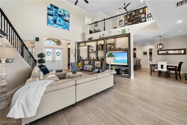 living room with french doors, wood-type flooring, ceiling fan, and a high ceiling