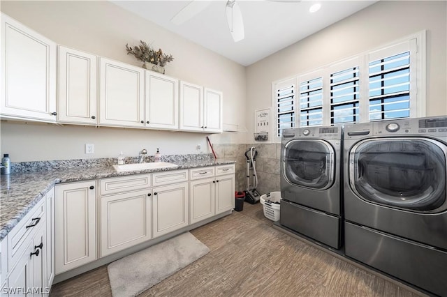 laundry room featuring ceiling fan, cabinets, wood-type flooring, sink, and washing machine and clothes dryer