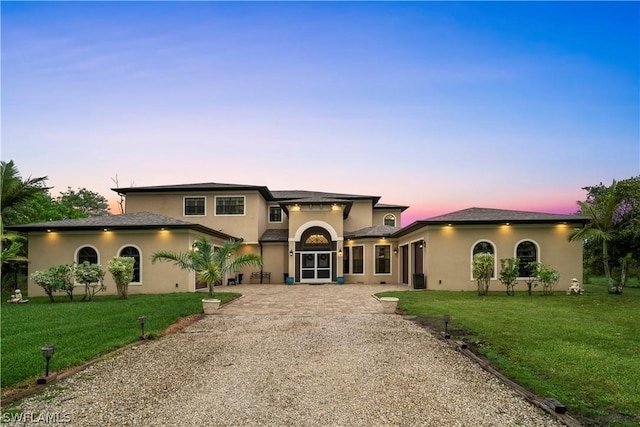 mediterranean / spanish-style home featuring a lawn and french doors