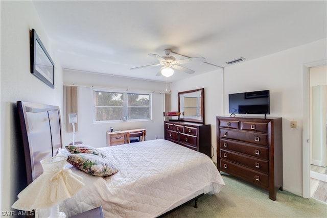 bedroom with light carpet, ensuite bath, and ceiling fan