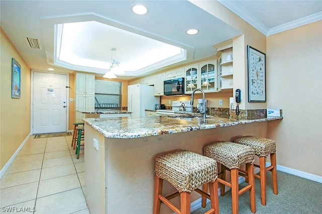 kitchen with kitchen peninsula, white appliances, a raised ceiling, a kitchen breakfast bar, and crown molding