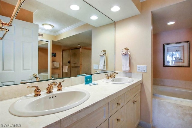 bathroom with toilet, a relaxing tiled bath, large vanity, and double sink