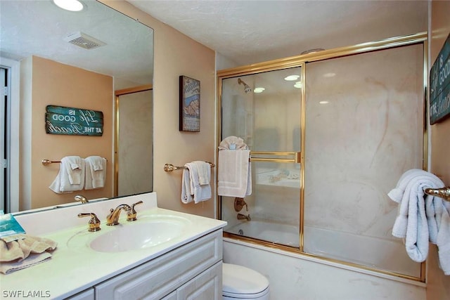 full bathroom featuring toilet, vanity, and bath / shower combo with glass door