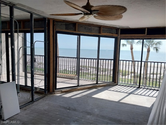 unfurnished sunroom featuring a water view, ceiling fan, and a wealth of natural light