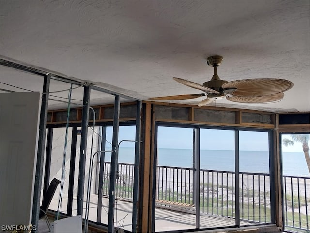 unfurnished sunroom with ceiling fan and a water view