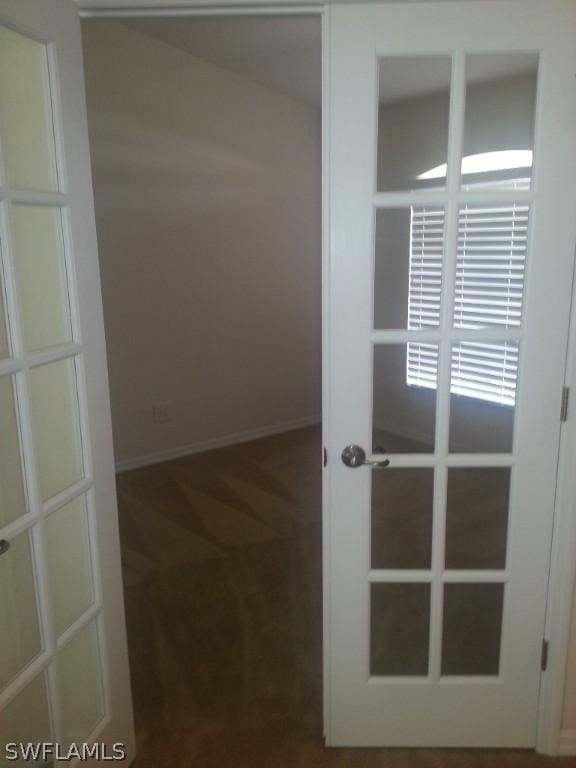 unfurnished room with dark colored carpet and french doors