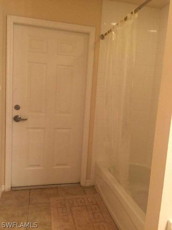 bathroom with tile flooring and shower / bathtub combination with curtain