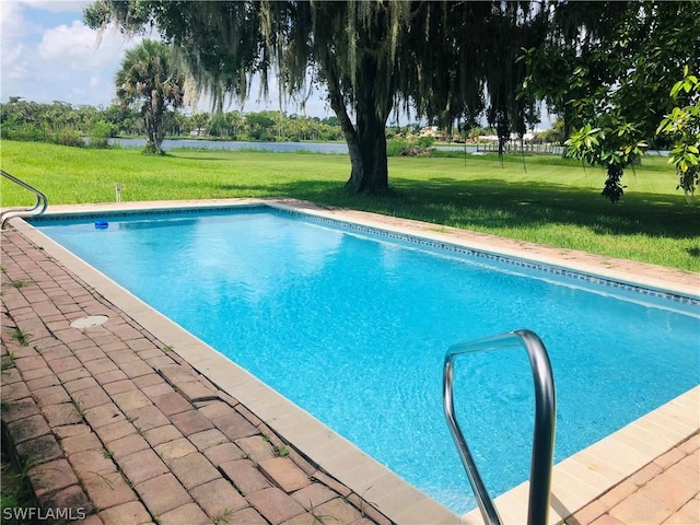 outdoor pool featuring a yard, a patio area, and a water view