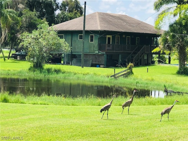 surrounding community with a water view and a lawn