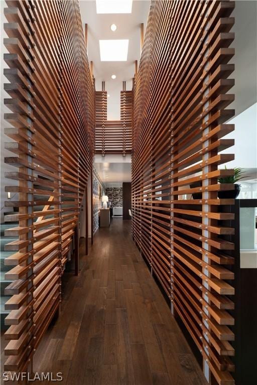 corridor featuring a towering ceiling and dark hardwood / wood-style flooring