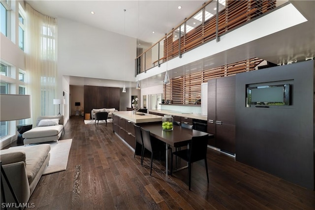 interior space featuring a high ceiling, hanging light fixtures, dark brown cabinets, and dark wood-type flooring