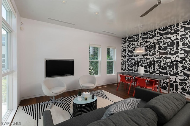 living room with plenty of natural light, ceiling fan, and dark wood-type flooring