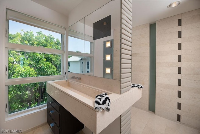 bathroom with oversized vanity, a healthy amount of sunlight, and tile flooring