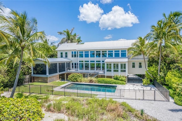 back of property with a fenced in pool