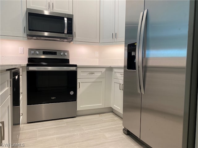 kitchen featuring appliances with stainless steel finishes, white cabinetry, and light hardwood / wood-style flooring