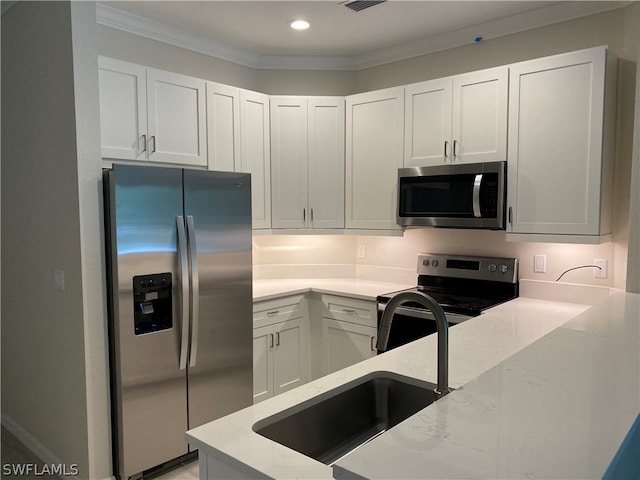 kitchen featuring stainless steel appliances, ornamental molding, white cabinets, light stone counters, and sink