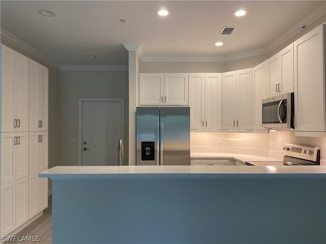 kitchen with ornamental molding, white cabinets, dark wood-type flooring, and stainless steel appliances