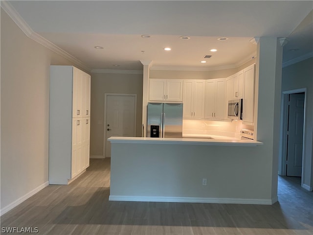 kitchen with dark hardwood / wood-style floors, ornamental molding, appliances with stainless steel finishes, and white cabinetry