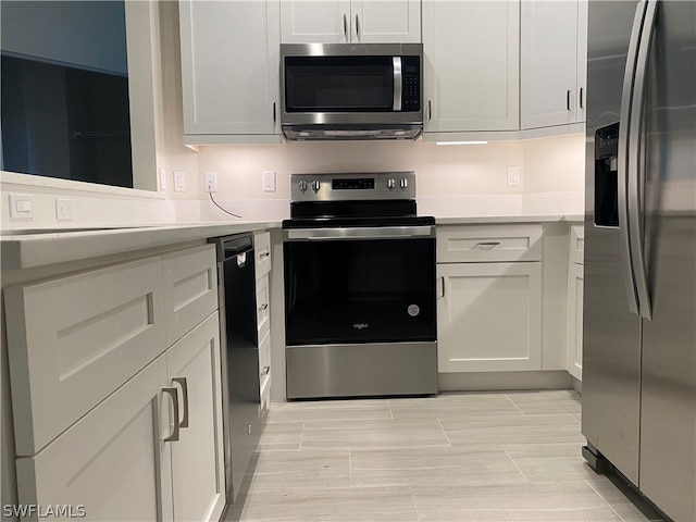 kitchen with white cabinets, light tile flooring, and stainless steel appliances