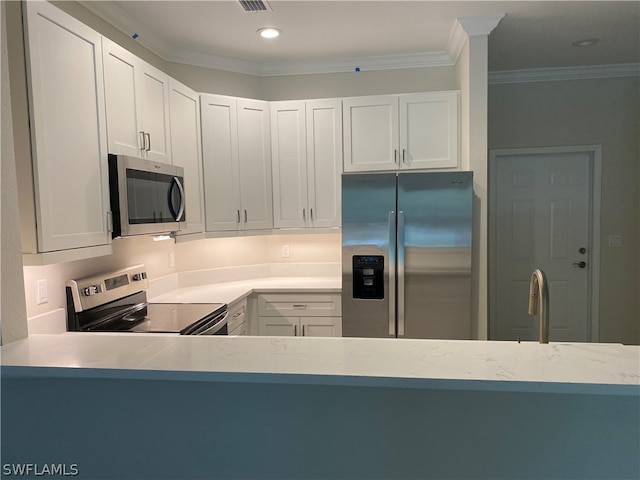 kitchen featuring ornamental molding, stainless steel appliances, and white cabinets