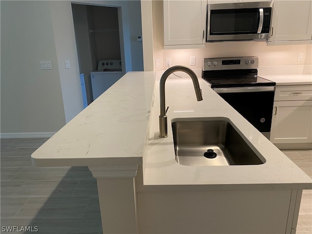 kitchen with light stone countertops, washer / clothes dryer, sink, and stainless steel appliances