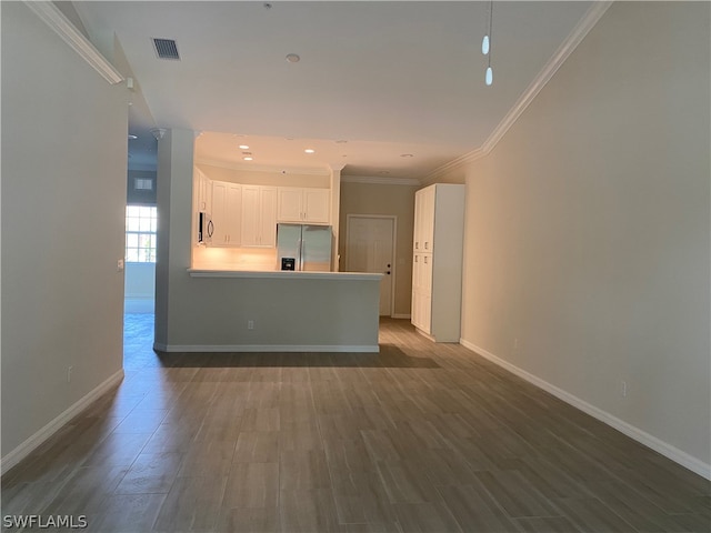 kitchen with appliances with stainless steel finishes, white cabinetry, crown molding, and wood-type flooring