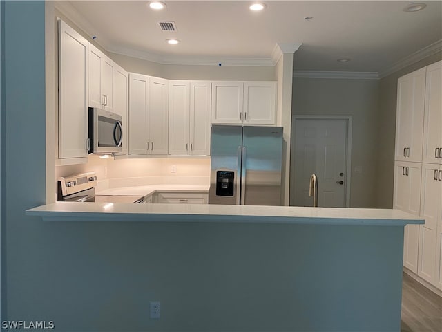 kitchen with hardwood / wood-style flooring, kitchen peninsula, ornamental molding, appliances with stainless steel finishes, and white cabinets