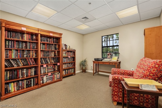 living area with a paneled ceiling and light colored carpet