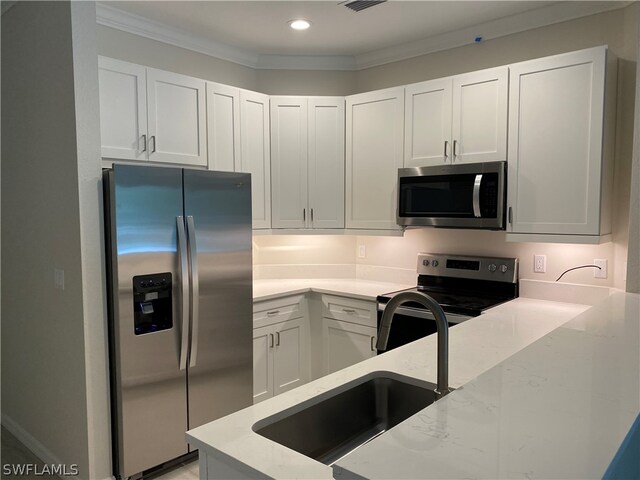 kitchen with stainless steel appliances, white cabinetry, crown molding, light stone counters, and sink