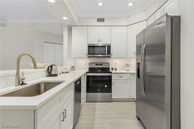 kitchen featuring appliances with stainless steel finishes, sink, light tile floors, white cabinets, and ornamental molding