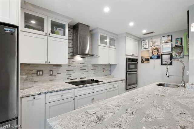 kitchen with white cabinetry, wall chimney exhaust hood, and stainless steel appliances