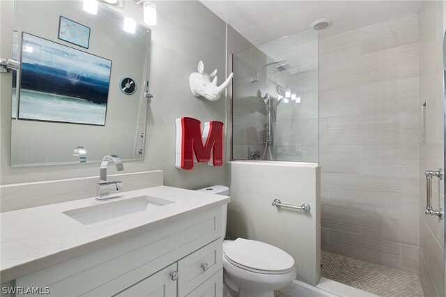 bathroom with a tile shower, vanity, and toilet