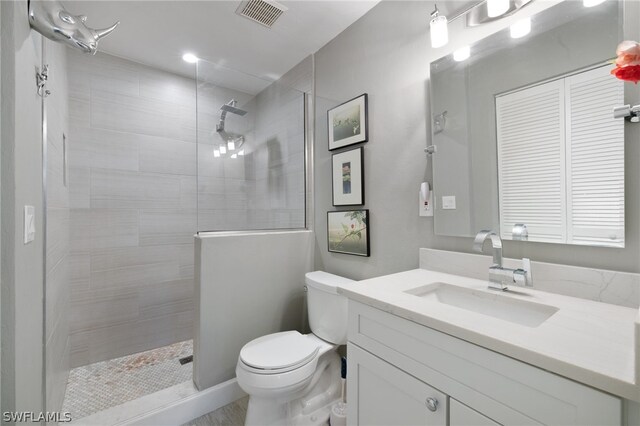 bathroom featuring tiled shower, vanity, and toilet