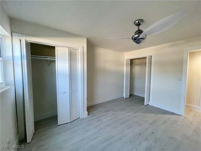 unfurnished bedroom with ceiling fan, light hardwood / wood-style flooring, and two closets