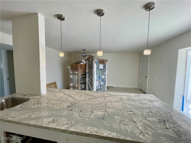 kitchen featuring light stone countertops and hanging light fixtures