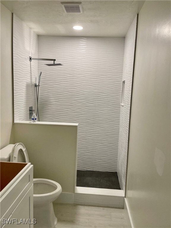 bathroom with vanity, hardwood / wood-style flooring, toilet, and walk in shower