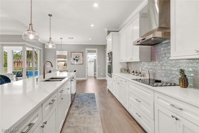 kitchen with black electric stovetop, hanging light fixtures, backsplash, wall chimney range hood, and white cabinetry