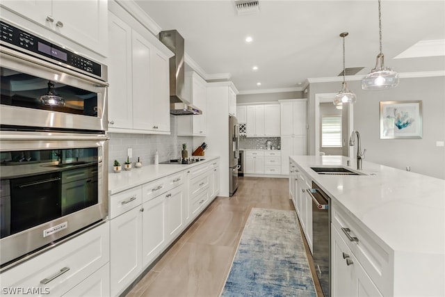 kitchen featuring backsplash, sink, stainless steel appliances, white cabinets, and wall chimney exhaust hood