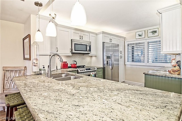 kitchen featuring sink, a kitchen breakfast bar, hanging light fixtures, appliances with stainless steel finishes, and light stone countertops